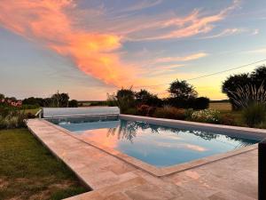 una piscina in un cortile con un arcobaleno nel cielo di Chambre 4 pers avec piscine chauffée & WiFi - FR-1-591-708 a Faverolles