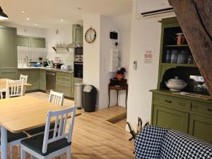 une cuisine et une salle à manger avec des armoires vertes et une table dans l'établissement Chambre Chambord avec piscine chauffée et parking privatif - FR-1-590-484, à Messas