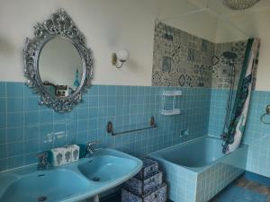 un bagno blu con lavandino e vasca di Chambre cosy avec petit-déj & services bien-être - FR-1-589-720 a Médonville