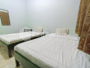 two beds in a room with white sheets at Orange inn RedPartner Madiun in Madiun +18 photos