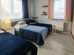 a bedroom with two beds and a lamp and windows at APARTAMENTY "LA VILLA" SUPERIOR III na parterze z prywatnym ogrodem, tarasem, parkingiem, blisko centrum, spokojna okolica in Kudowa-Zdrój