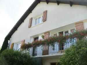 a white building with red flowers on a balcony at Chalet cosy avec cheminée et animaux acceptés - FR-1-585-144 in Cousancelles