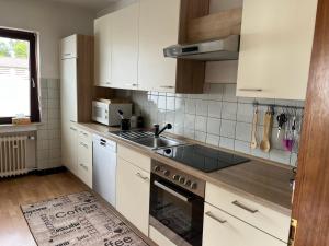 a kitchen with white cabinets and a sink at Ferienwohnung in Heuchelheim in Heuchelheim