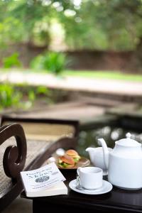 a table with a tea pot and cups on it at Sigiriya Village in Sigiriya
