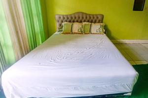 un lit avec des draps blancs et des oreillers dans une chambre dans l'établissement Hotel Dienda Hayu, à Lombok