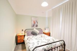 a bedroom with a bed and two night stands and a window at Cosy Sun-Filled Cottage in Tenterfield