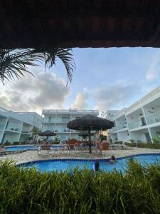 a pool with chairs and an umbrella in front of a hotel at FlatsJasmim, Apartamento completo Jacumã-Conde in Conde