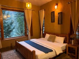a bedroom with a bed with a large window at Doghari Chalets Jibhi by Himtrek Stays in Jibhi +33 photos
