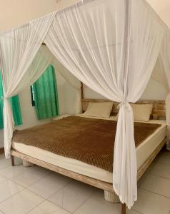 a bedroom with a canopy bed with curtains at the village rua beach homestay in Rua