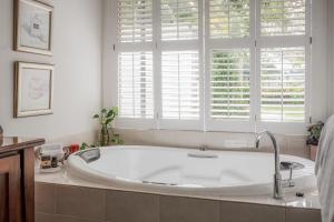 baño con bañera blanca y ventana en Jasmine's Barossa Valley Cottage, en Lyndoch