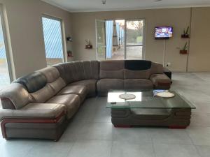a brown leather couch in a living room with a table at Riverside Recreation Lodge in Katima Mulilo