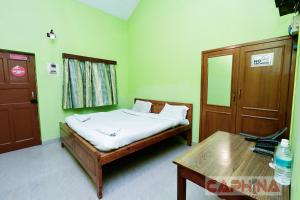 a bedroom with a bed and a table in it at Caphina Coastal Comforts in Benaulim