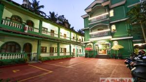 a large green building with motorcycles parked in a parking lot at Caphina Coastal Comforts in Benaulim