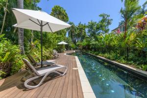 an umbrella and lounge chairs next to a swimming pool at Villa 4 on Murphy in Port Douglas
