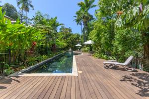 a wooden deck with a swimming pool and a lounge chair at Villa 4 on Murphy in Port Douglas