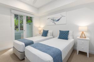 two beds in a white room with a window at Villa 4 on Murphy in Port Douglas +17 photos