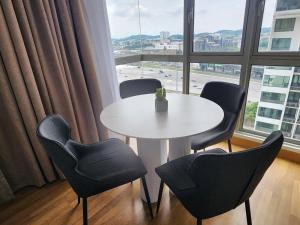 a table and chairs in a room with a large window at One South 3bedroom, MRT to TRX in Seri Kembangan