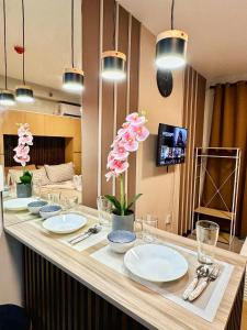 una mesa con platos blancos y flores rosas. en Saekyung Condo with Balcony and Pool Near Mactan Airport, en Lapu Lapu City