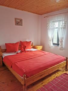 a bedroom with a large bed with red sheets and a window at АРНАТА КЪЩА in Yakovtsi