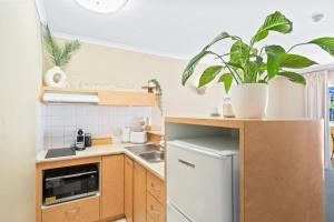 a small kitchen with wooden cabinets and a white refrigerator at Stylish CBD retreat - 8 Il Palazzo in Cairns