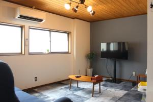 a living room with a table and a tv at Hotel Relation in 門司港 in Kitakyushu