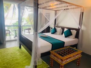 a bedroom with a canopy bed and a table at Lake Duwa Hotel in Ambalangoda