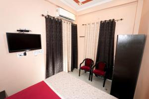 Cette chambre comprend un lit, deux chaises et une télévision. dans l'établissement Krishna Kunj Homestay & Resort Ayodhya, à Faizābād