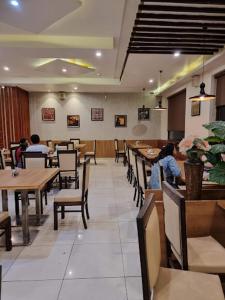 a restaurant with tables and chairs and people sitting at tables at Hotel President in Bharwain
