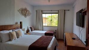 um quarto de hotel com duas camas e uma janela em Pouso Flor da serra em Tiradentes