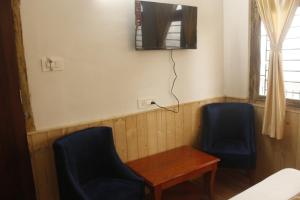 a room with two chairs and a table and a tv at Priyatam Stays in Darjeeling