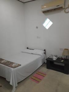 a white bedroom with a bed and a table at Aruna Villa in Unawatuna