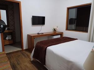 um quarto de hotel com uma cama e uma televisão em Pouso Flor da serra em Tiradentes
