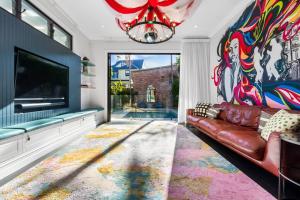 a living room with a couch and a large tv at Colourwave Terrace - A Technicolor Poolside Stay in Newcastle