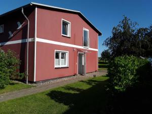 a red and white house with a yard at Ferienwohnungen am Bach in Marlow +24 photos