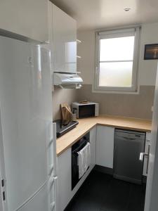 a small kitchen with a refrigerator and a microwave at Appartement 2 chambres Versailles in Versailles