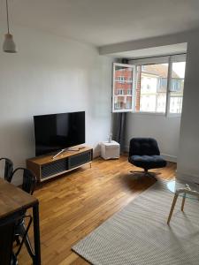 a living room with a flat screen tv and a chair at Appartement 2 chambres Versailles in Versailles