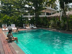 a woman is sitting in a swimming pool at Bahandi Hotel in General Luna
