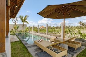 a swimming pool with two chairs and an umbrella at Pucuk Ubud Villa in Ubud
