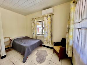 a bedroom with a bed and a chair and a window at 3 Bed House - Sleeps 6 - Garden - Parking - Wifi in Paramaribo