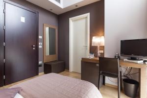 a bedroom with a bed and a desk and a television at Hotel Michelangelo in Forlì