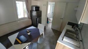 マリーナ・ディ・カンポにあるVictoria Mobilehome by Ville degli Uliviのテーブルと冷蔵庫のある小さなキッチン