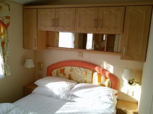 a bedroom with a bed with a wooden headboard at 8 Berth Central heated Golden Palm (Aspen GP) in Chapel Saint Leonards