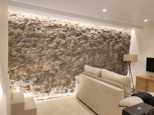 a living room with a couch and a stone wall at Casa Cueva Un Rinconcito en Setenil in Setenil