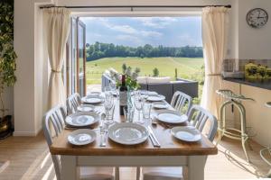 a table with plates and glasses on it in a room with a window at Holly Cottage in Cranleigh