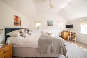 a white bedroom with a bed and a desk at Holly Cottage in Cranleigh