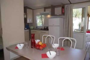 a kitchen with a table with a bowl of fruit on it at Camping 4 étoiles - Parc aquatique - eebaha in Hyères