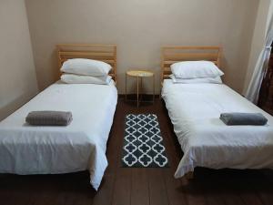 two twin beds in a small room with a rug at Preece's Homestay in Kuala Lumpur