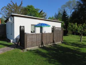 a house with an umbrella over a wooden fence at Bungalow Alms in Ribnitz-Damgarten
