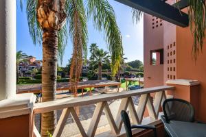 a balcony with a palm tree and a table and chairs at El Rincon del Golf II PLUS by Ĥ - Isla Canela Golf GRHII27P30 in Isla Canela