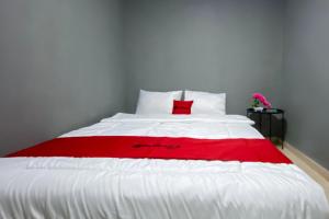 a red and white bed with a red blanket on it at RedDoorz at Marina City Waterfront in Pembunuh